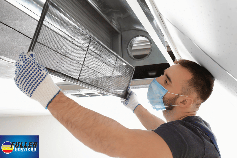 Man wearing gloves and mask checking HVAC ducts and filter to winterize system in Northern Alabama