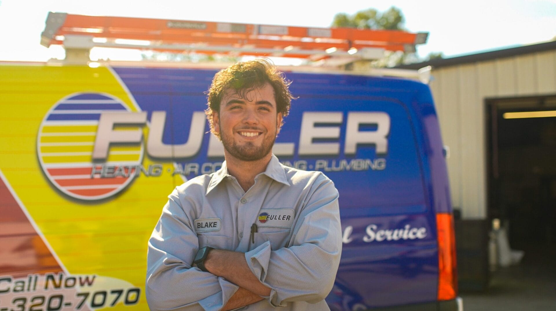 Fuller Services HVAC technician standing confidently in front of a branded service van, representing professional heating, air conditioning, and plumbing service.