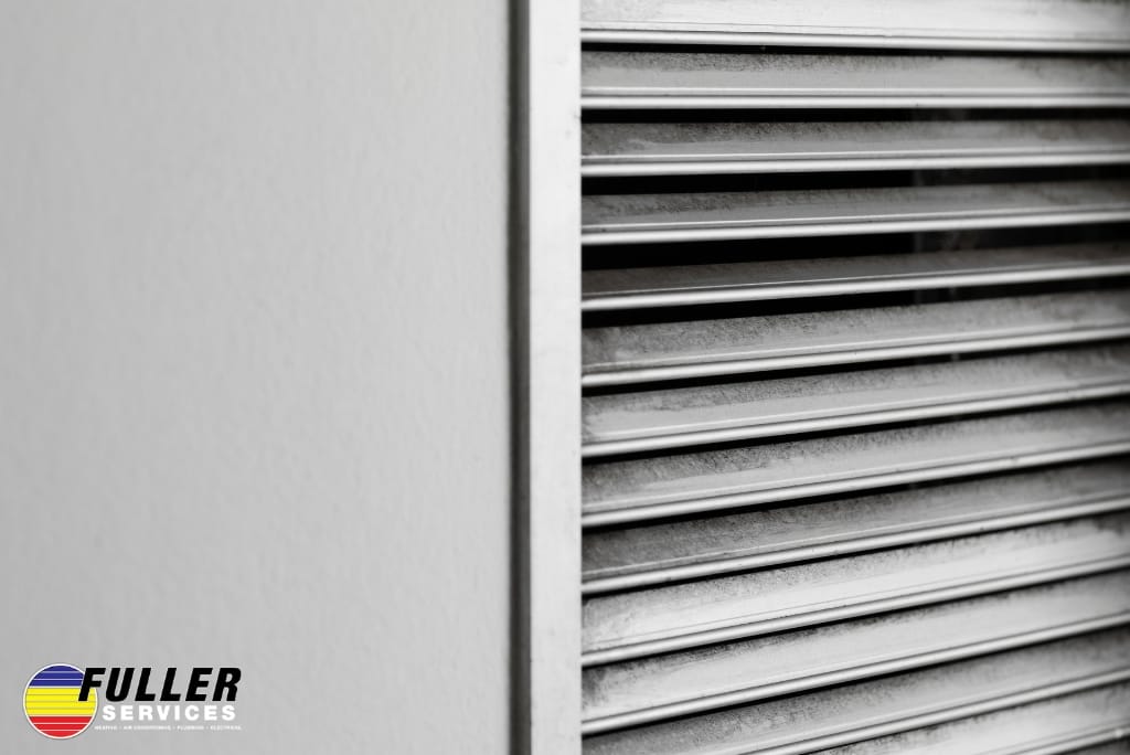 Close-up of an HVAC air vent grille with visible dust and dark buildup.