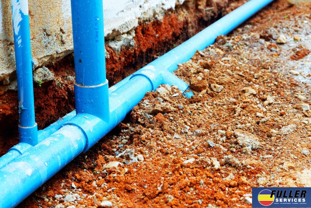 Blue sump pump discharge pipes installed beside a foundation for a system that runs constantly.