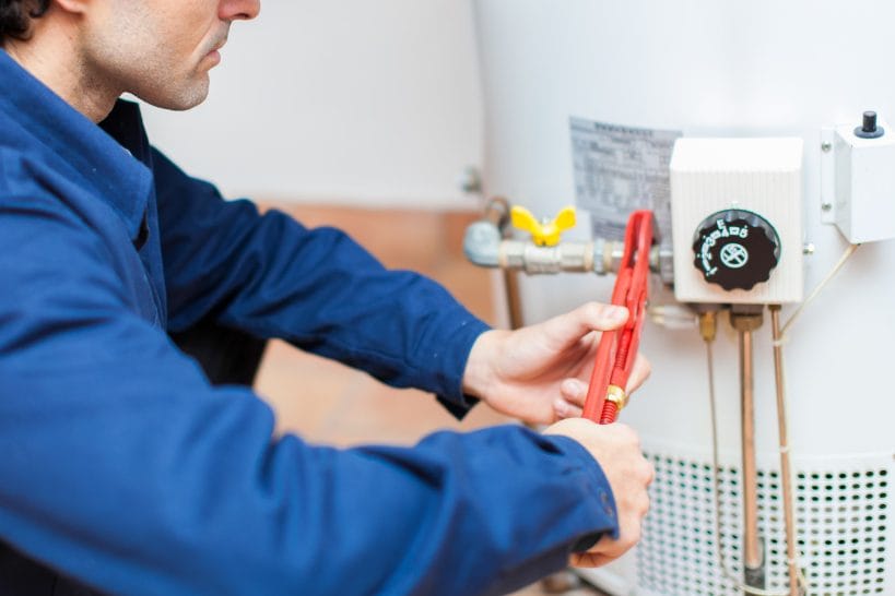 Plumbing technician repairing a water heater affected by hard water and mineral buildup.