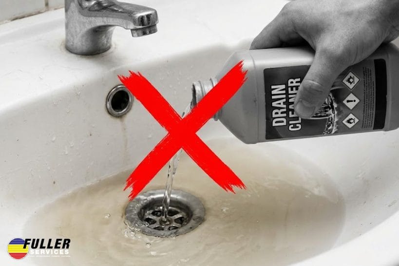 Chemical drain cleaner being poured into a clogged sink with a red X warning against its use.